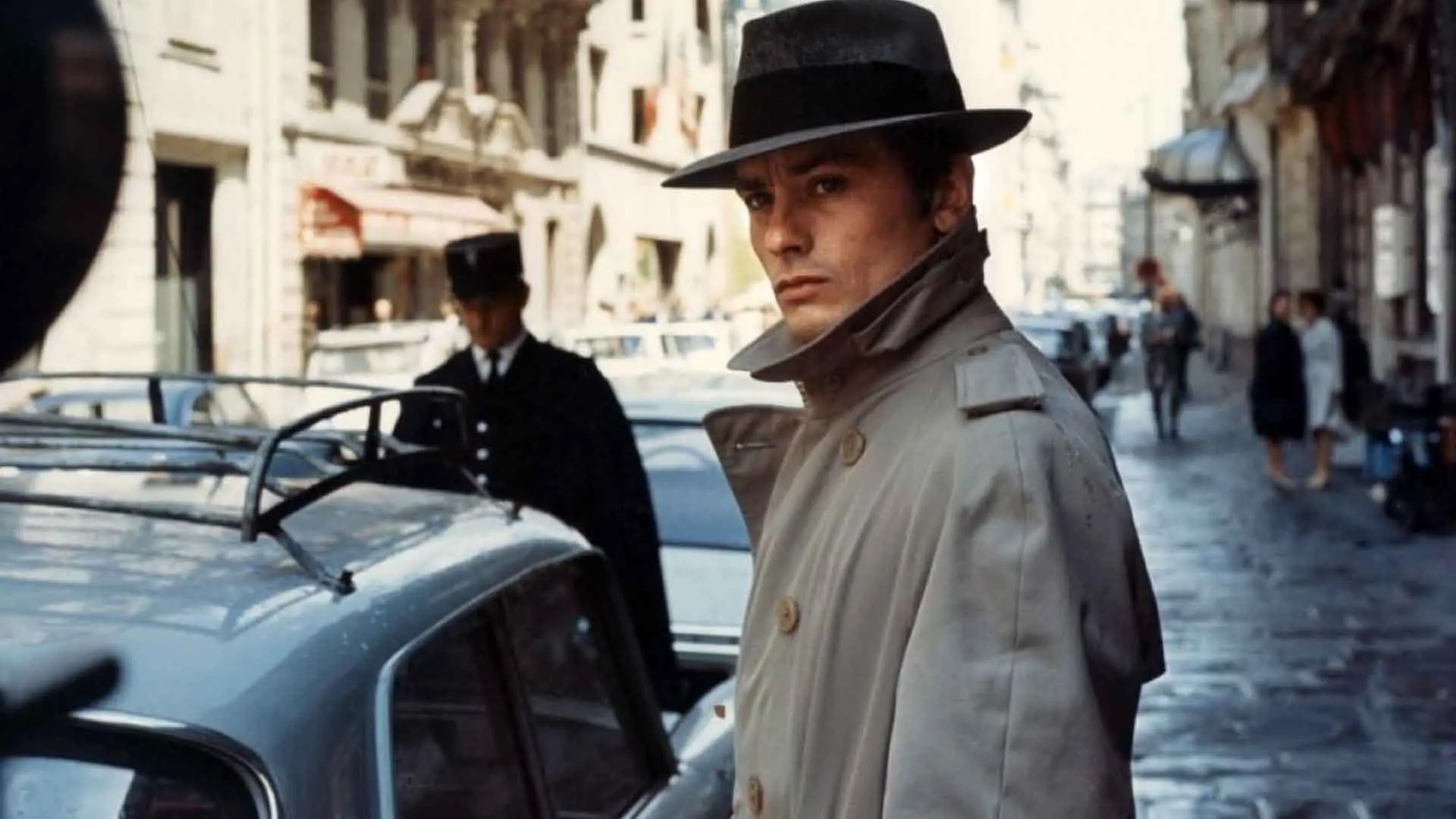 آلن دلون در فیلم Le Samouraï کنار یک ماشین ایستاده است