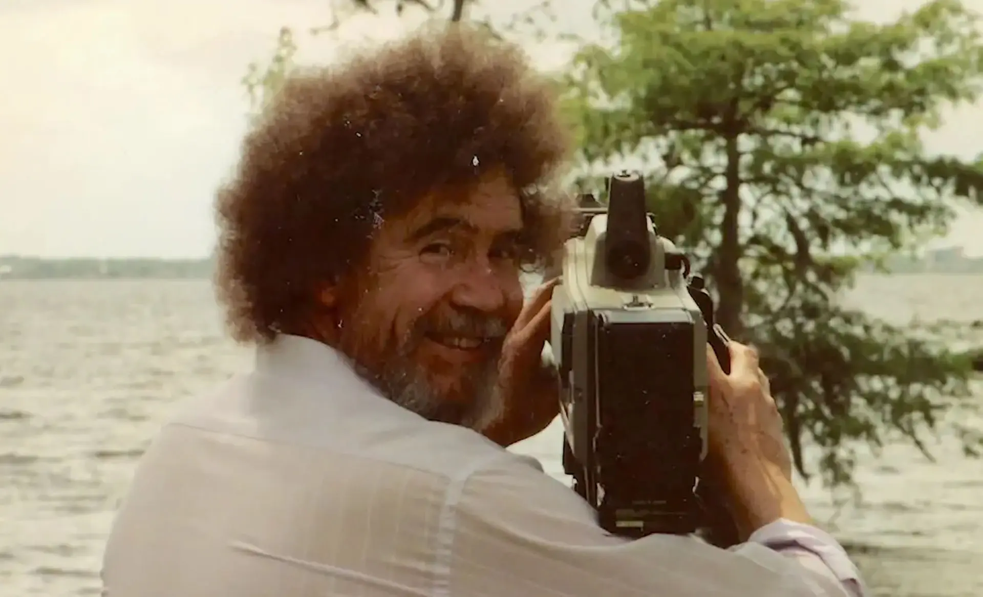 باب راس دوربین به دست در مستند Bob Ross: Happy Accidents, Betrayal & Greed